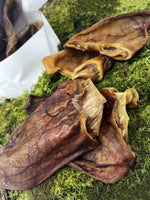 Floppy Ear Air Dried Pig Ears Natural Dog Chew close up showing crunchy texture on moss