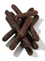 Close-up pile of dark brown Floppy Ear Venison Sausages dog treats