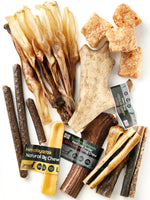 Flat lay of all contents from Floppy Ear Large Puppy Box – Himalayan yak chews, Scottish Highlands red deer antler, fallow deer antler, beef strips and natural treats on white background