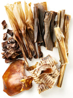 Flat lay assortment of natural dog chews and treats from Floppy Ear – variety of premium single-ingredient chews including beef cubes, trachea rings, pig ear and skins